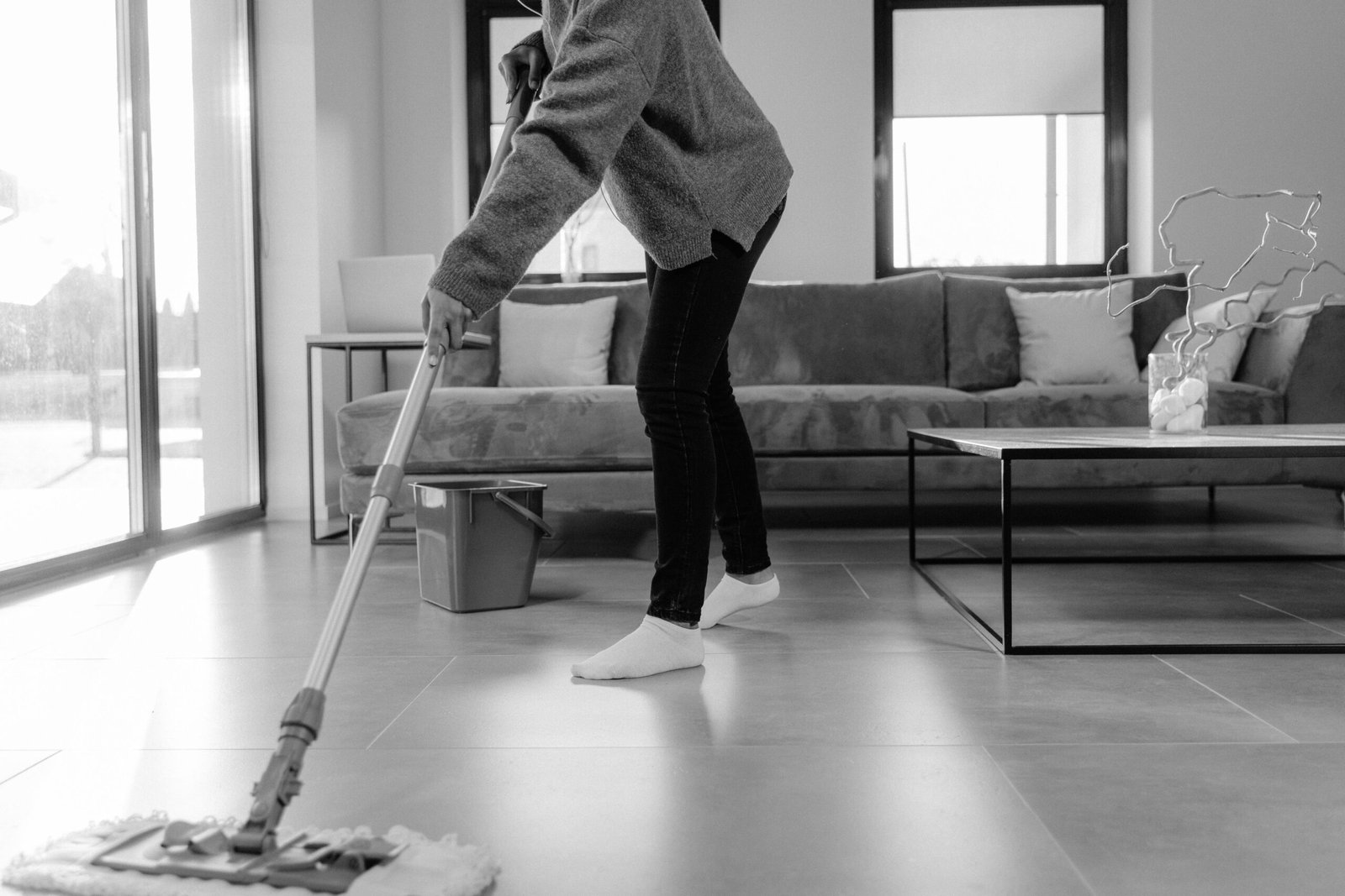 A person mopping the floor in a clean living room as part of a daily home cleaning routine