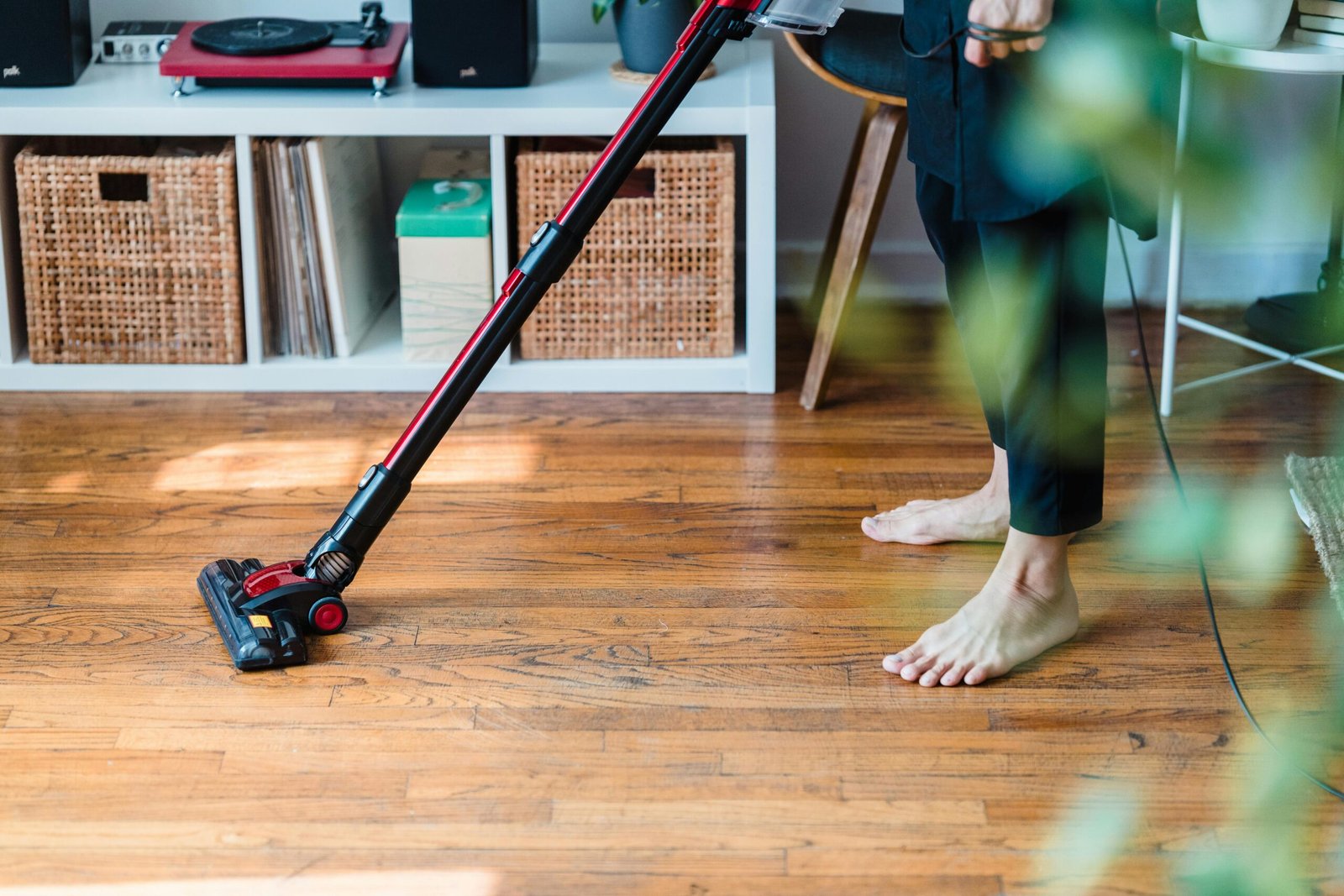 A person vacuuming a wooden floor at home as part of a simple daily cleaning routine